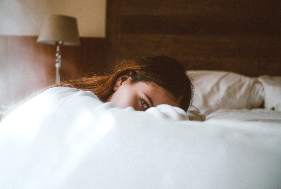 woman laying on bed wearing glossier boy brow dupe